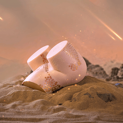 Realistic male masturbator with textured pink skin and gold speckles, nestled in desert sand under warm glow