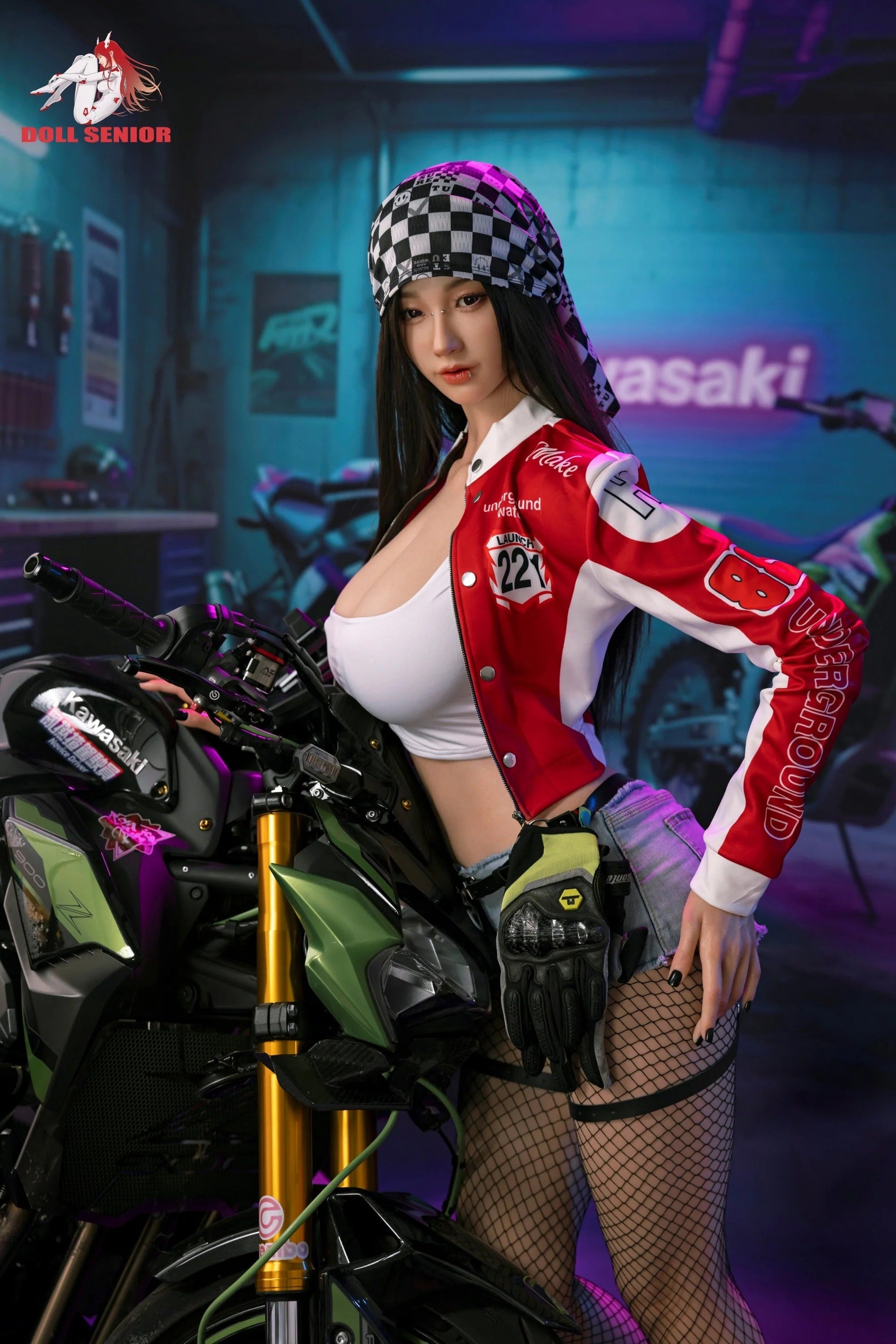 Realistic female doll in red racing jacket, checkered bandana, fishnet stockings, posing beside green Kawasaki motorcycle in garage.