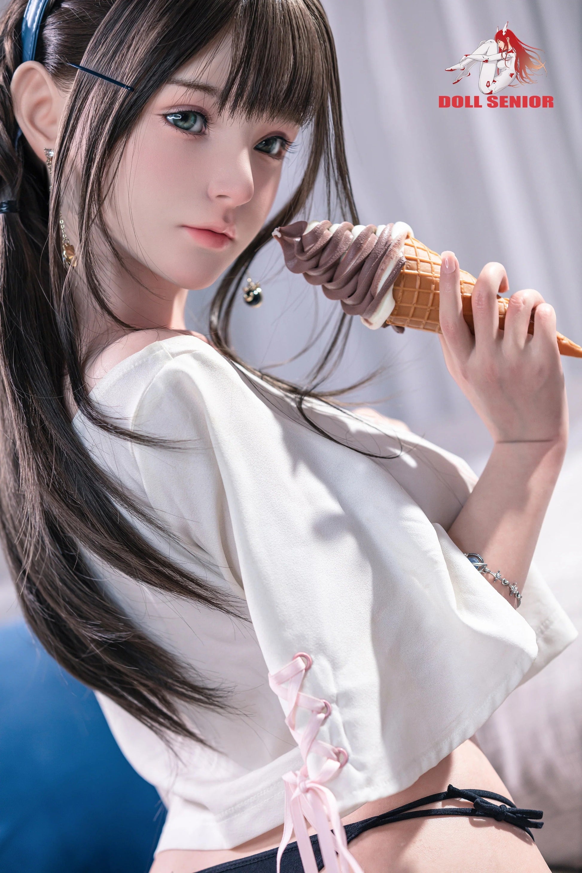 Realistic female doll with long brown hair, green eyes, holding chocolate ice cream cone, wearing white top with pink lace.