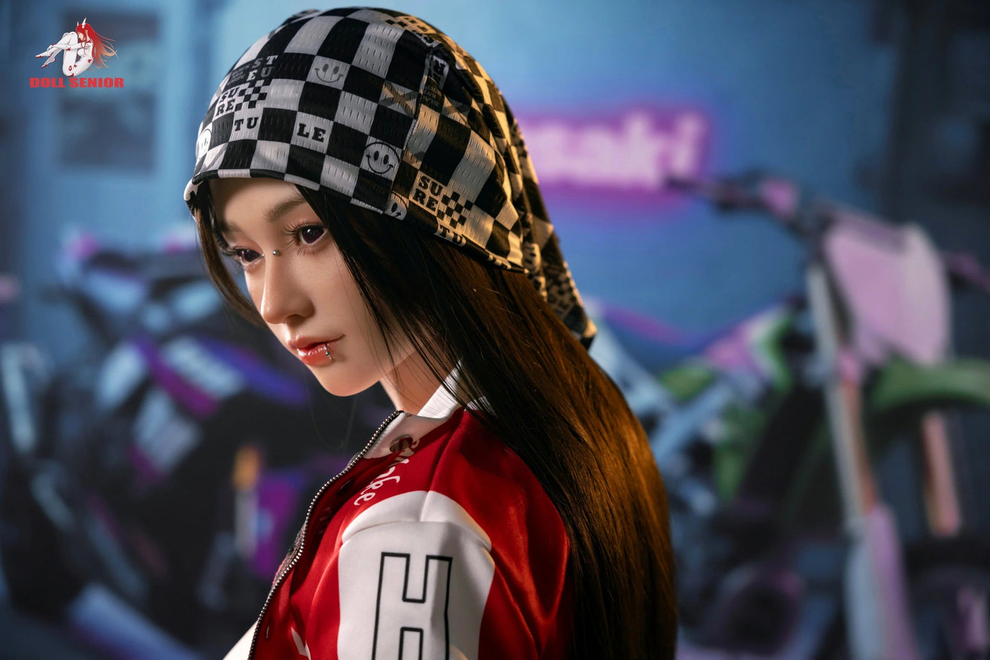 Realistic doll with long dark hair, nose and lip piercings, wearing checkered beanie and red-white jacket.