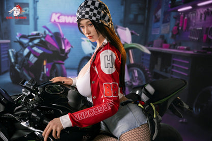 Realistic female doll in red racing jacket and checkered beanie, seated on motorcycle in garage setting