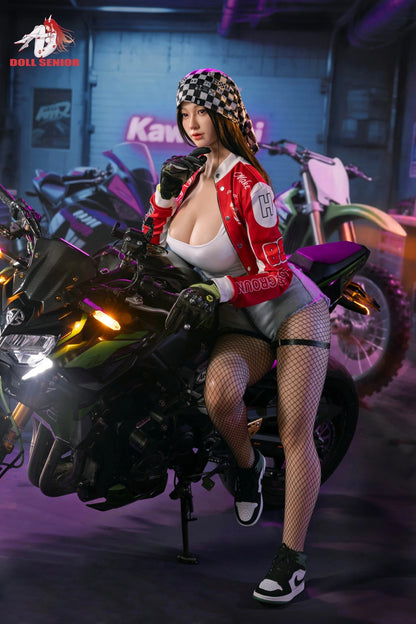 Realistic female doll in red racing jacket, fishnet stockings, posing on motorcycle in garage with neon lights