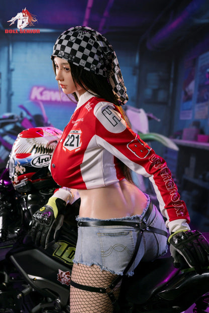 Realistic female doll in red racing jacket, denim shorts, and fishnet stockings, posed on a motorcycle with checkered bandana.