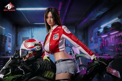 Realistic female doll in red racing jacket and denim shorts, posed on motorcycle in garage setting
