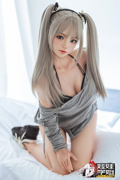 Realistic doll with silver pigtails, soft skin texture, wearing gray top and black lingerie, posed on white bedding.