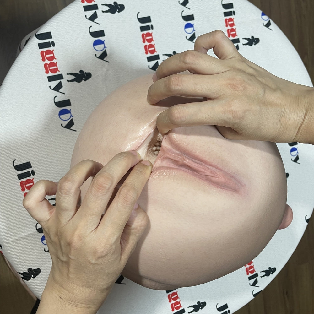 Realistic silicone male masturbator with detailed labia and textured interior, shown with hands demonstrating flexibility