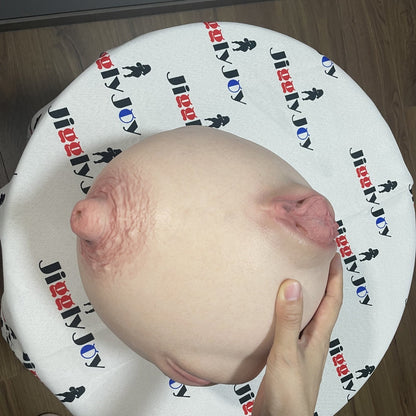 Realistic male masturbator with detailed labia and natural skin texture, held in hand on branded cloth.