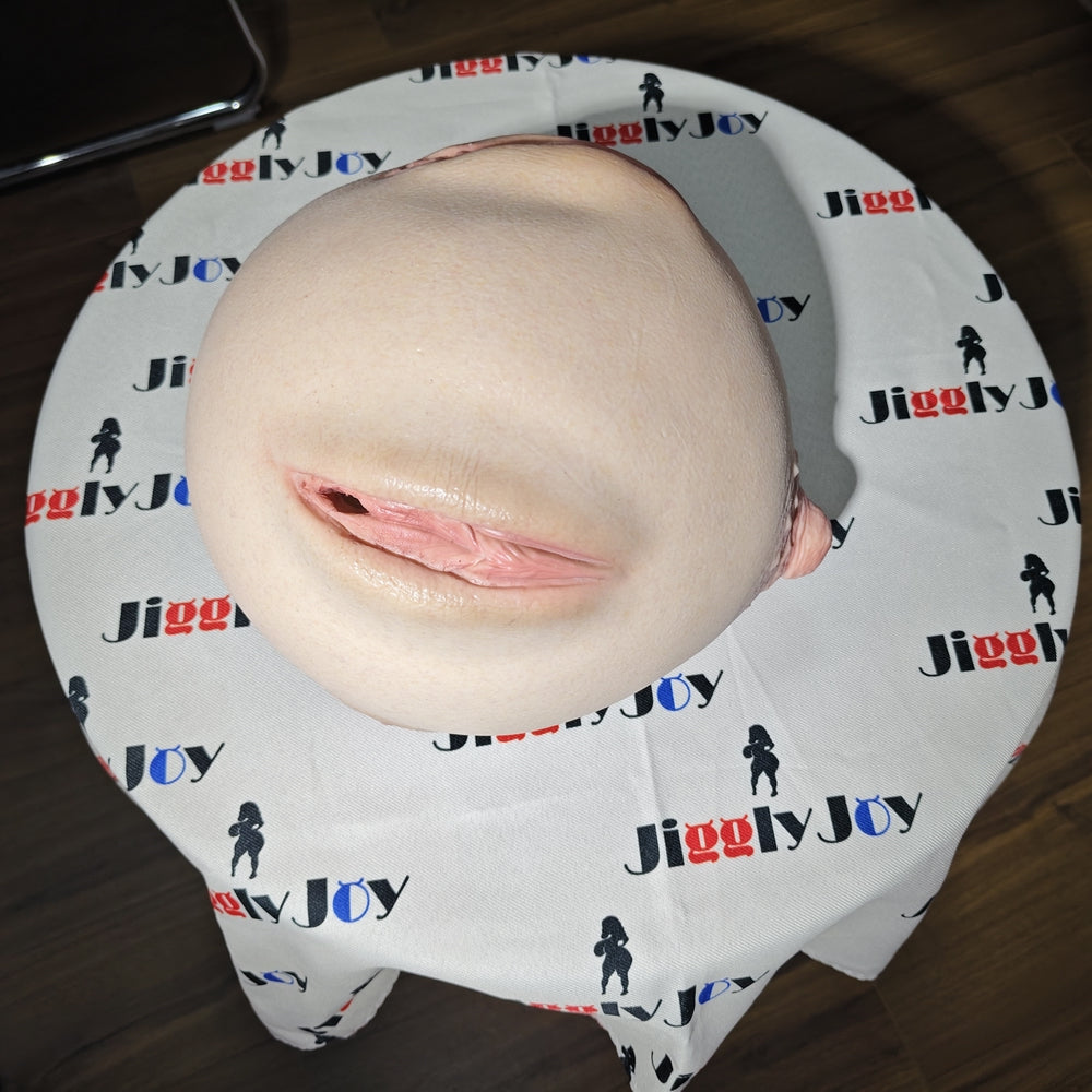 Realistic flesh-toned male masturbator with detailed labia and soft texture, displayed on branded cloth