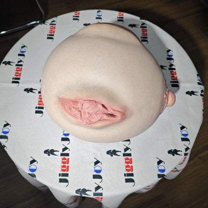 Realistic male masturbator with detailed pink interior and soft skin texture on branded cloth