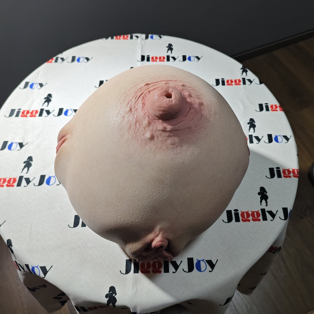 Realistic flesh-toned male masturbator with detailed vaginal and anal openings, soft silicone texture, displayed on branded fabric