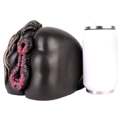 Realistic black and pink textured male masturbator with detailed folds, shown beside a can for scale